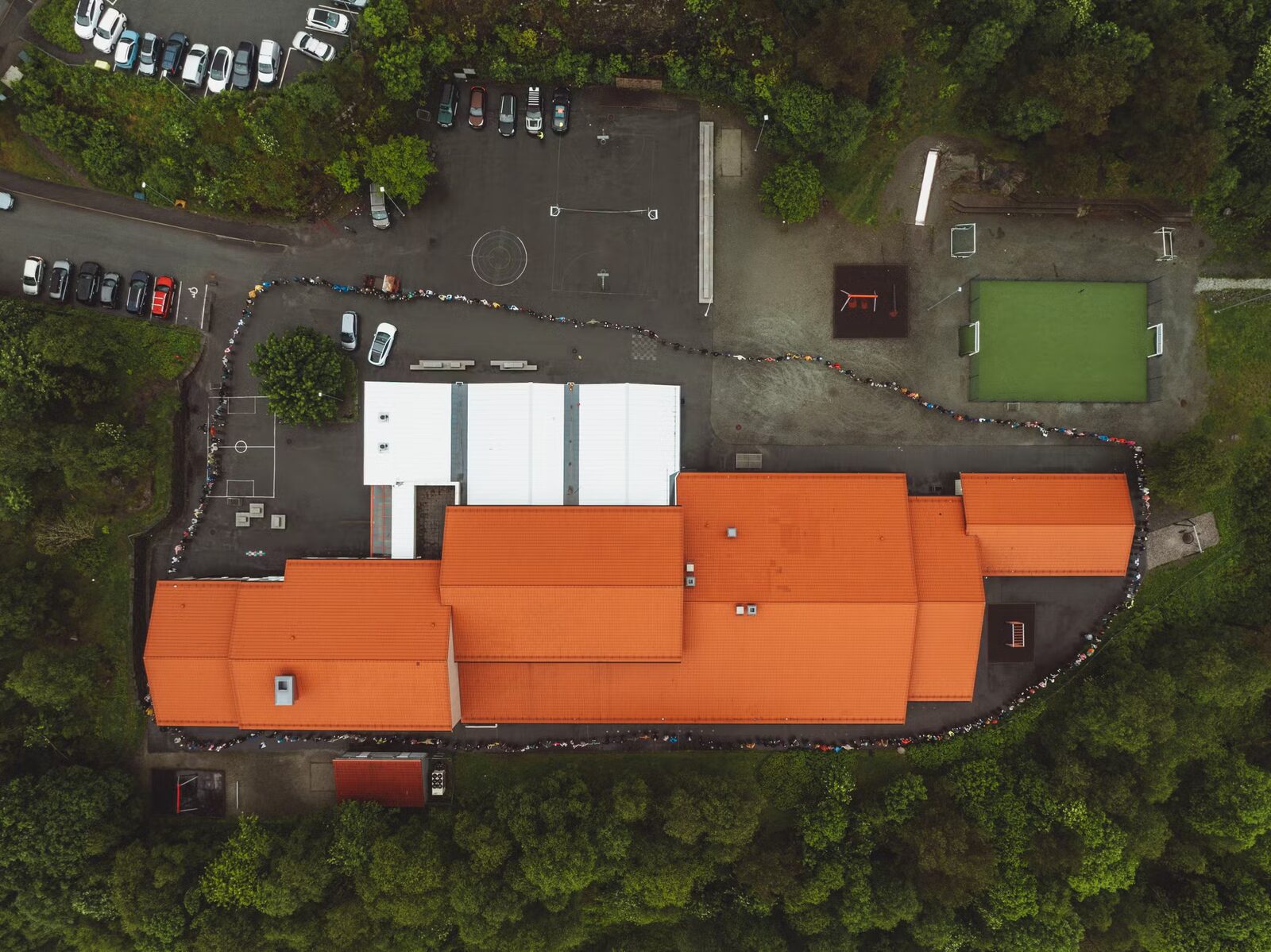 Dronefoto ovanfrå av Grasdal skule med ei ubroten menneskekjede av born og vaksne heilt rundt heile skuleanlegget.